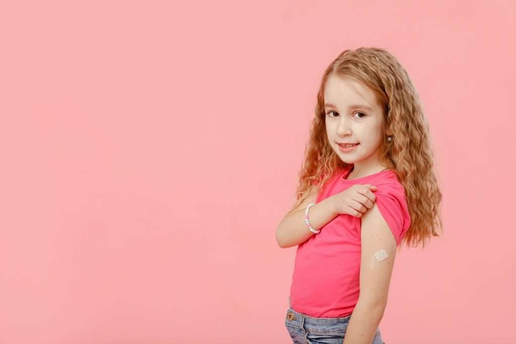 Vaccination concept. cute little girl, preschooler, with a band-aid on her shoulder, received