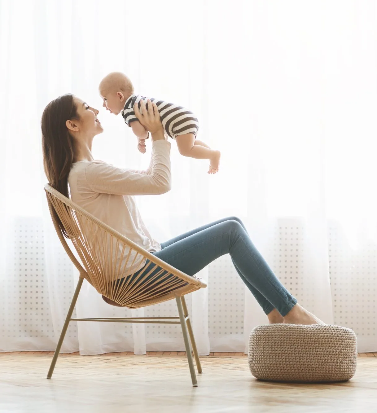 Mother sitting in chair and lifting her newborn child up